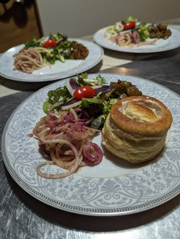 Vol-au-vent doré servi avec une salade et des oignons rouges marinés